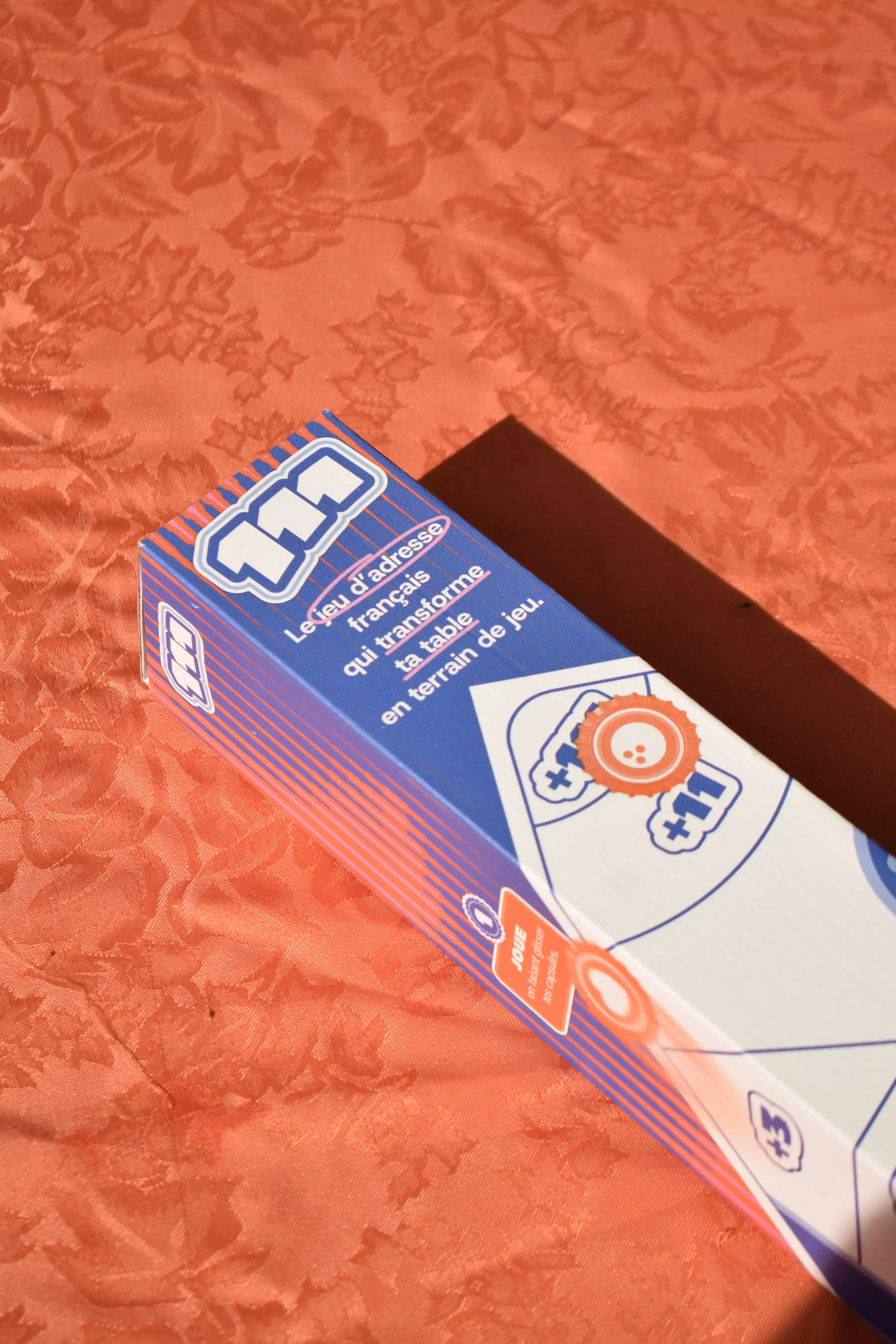 Photo du packaging du jeu Le 111 sur une table au soleil